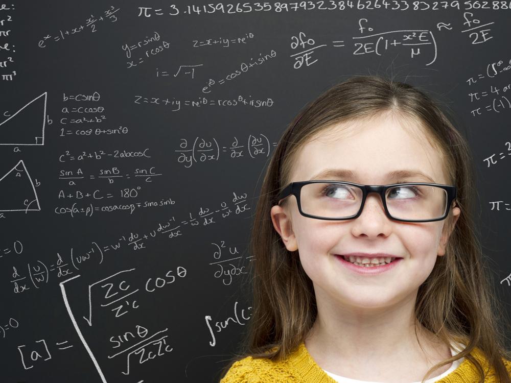 Smart young girl stood infront of a blackboard