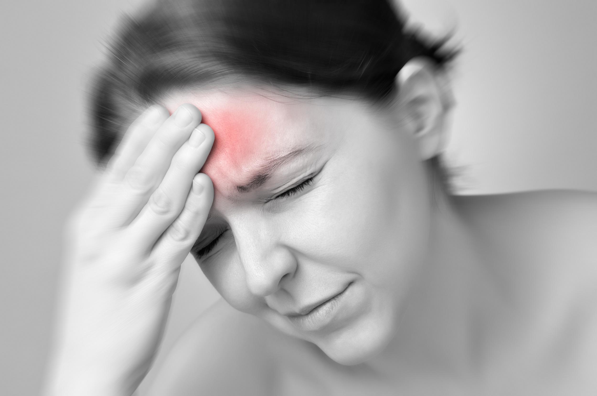 A young woman holding her painful head