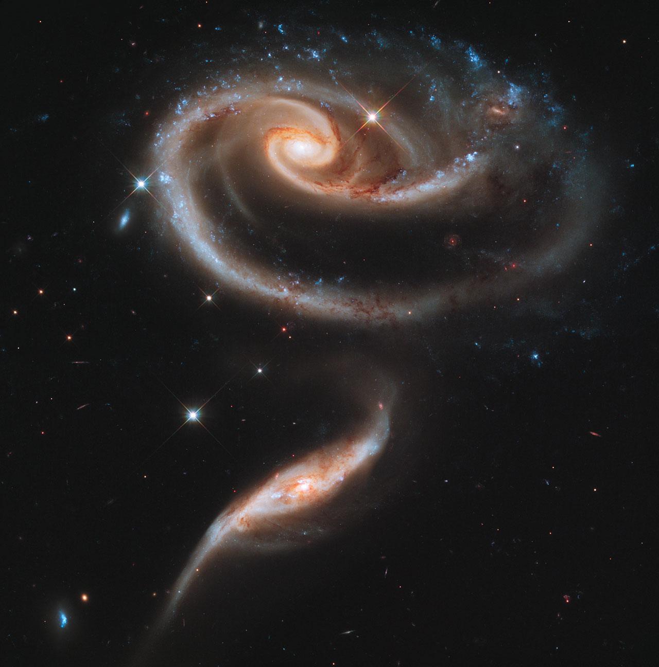 This image of a pair of interacting galaxies called Arp 273 was released to celebrate the 21st anniversary of the launch of the NASA/ESA Hubble Space Telescope.  The distorted shape of the larger of the two galaxies shows signs of tidal interactions with the smaller of the two. It is thought that the smaller galaxy has actually passed through the larger one.