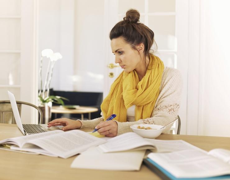 Young university student using laptop and books in studying at home