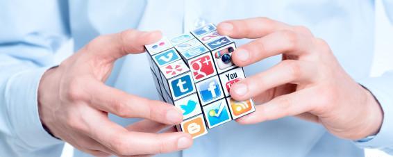 Businessman solving rubik's cube with logotypes of well-known social media brand's.