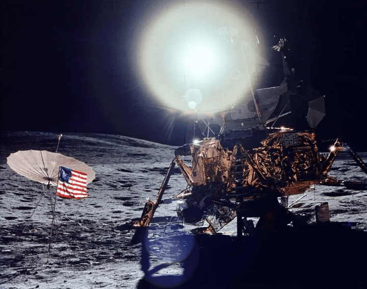 A moon with a flag and a satellite</p>
<p>Description automatically generated
