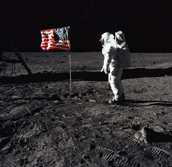 A person in a white suit standing on the moon with a flag</p>
<p>Description automatically generated