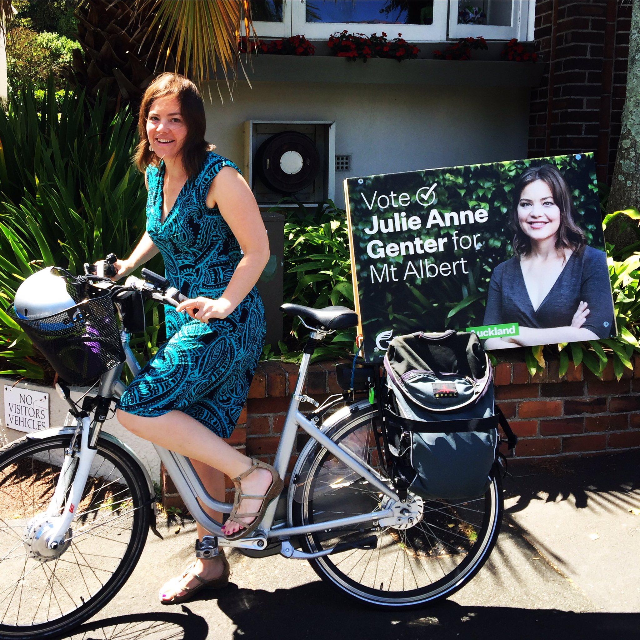 النائبة النيوزيلاندية جولي آن جينتر تقود دراجتها في الشارع خلال حملتها الانتخابية، وتضع على الدراجة لافتة مكتوب عليها "صوتوا لجولي آن جينتر"
