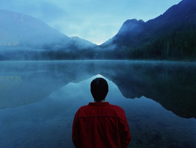 Man standing by lake covered with fog, rear view الرؤية في العين